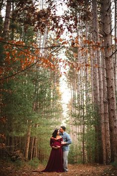 a man and woman standing in the middle of a forest