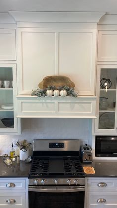 a stove top oven sitting inside of a kitchen next to white cabinets and counter tops