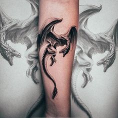 a black and white photo of a dragon tattoo on someone's leg with wings