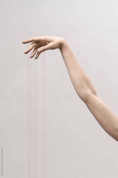 a woman's arm and hand reaching for string