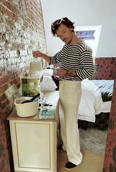 a man standing next to a fish tank on top of a wooden table in front of a brick wall