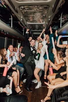 a group of people standing on top of a bus holding up bottles and champagnes