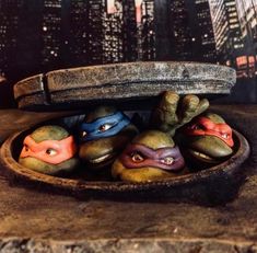 turtles in a wooden bowl with their heads painted like teenage mutant ninjas on them