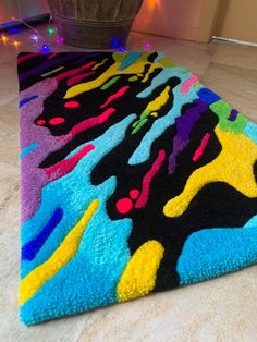 a multicolored area rug on the floor next to a potted plant