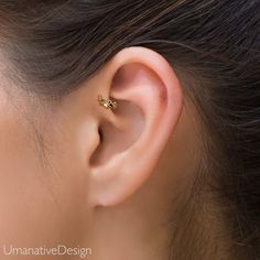 a woman's ear is shown with a small gold ring on the end of it