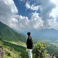 a man standing on top of a mountain looking at the valley and mountains in the distance