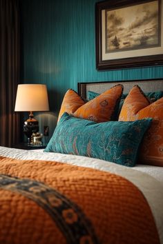 a neatly made bed with orange and teal pillows in a hotel room at night