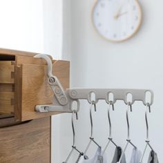 a clock is hanging on the wall next to a coat rack with several coats in it