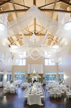 a room filled with lots of tables covered in white tablecloths and centerpieces