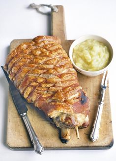 a large piece of meat sitting on top of a cutting board next to a bowl of mashed potatoes