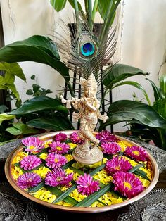 there is a plate with flowers in it and a peacock on the table next to it