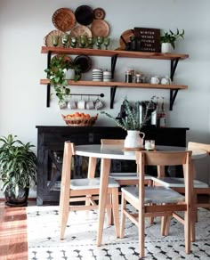 a dining room table with chairs and shelves above it