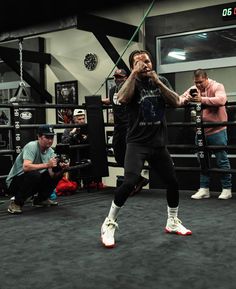 a man standing in a boxing ring with his hands on his hips and other people watching