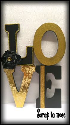 the word love spelled in gold and black with a rose on it's side