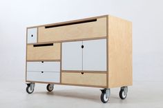 a wooden cabinet with drawers and wheels on the bottom, in front of a white background