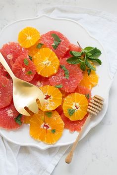 grapefruit and orange slices on a white plate with gold utensils