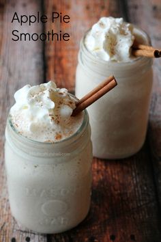 two mason jars filled with apple pie smoothie and topped with whipped cream, cinnamon sticks