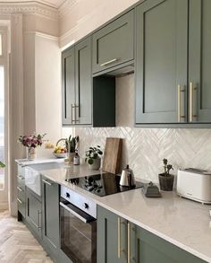 a kitchen with green cabinets and white counter tops