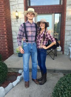 a man and woman standing in front of a brick building wearing cowboy hats, jeans and overalls