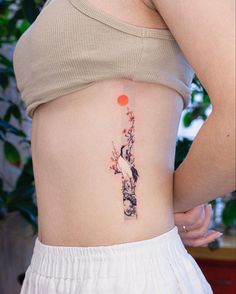 a woman's lower back tattoo with an image of a tree and a bird on it