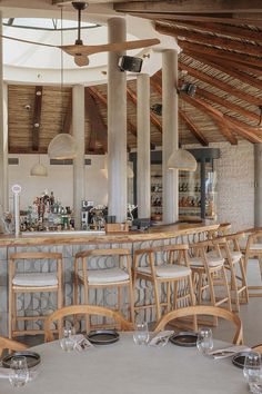 an empty restaurant with tables and chairs in front of the bar, filled with wine glasses