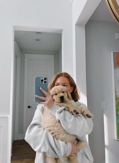 a woman holding a dog while taking a selfie with her cell phone in front of her face