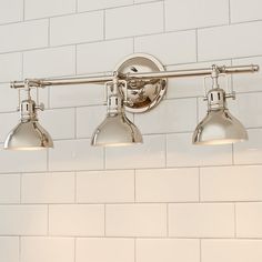 three light bathroom fixture with white tiles in the back ground and on the wall behind it