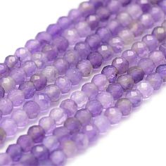 purple glass beads are lined up on a white surface