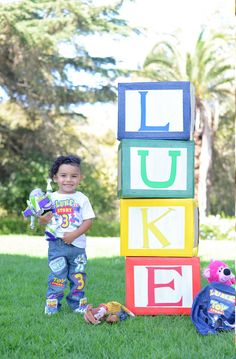 a little boy standing in front of blocks that spell out the word luk e