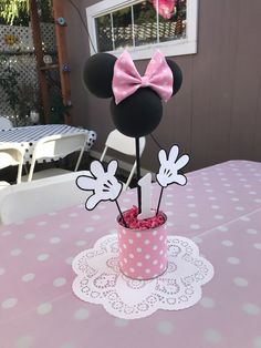 a minnie mouse centerpiece with pink roses in a polka dot cup on a table