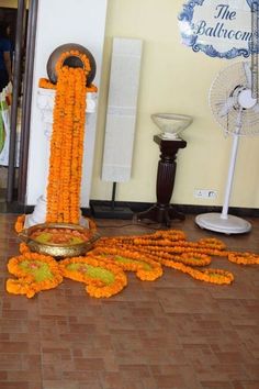 an arrangement of orange flowers on the ground in front of a doorway with fans and fan