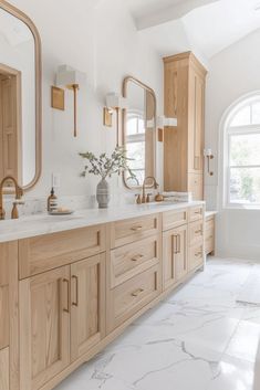 a large bathroom with two sinks and mirrors on the wall, along with marble flooring