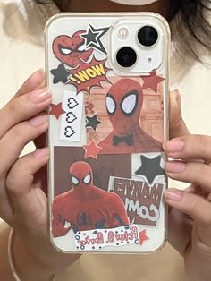 a woman holding up her phone case with spiderman stickers on it