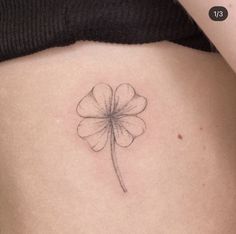 a small four leaf clover tattoo on the back of a woman's stomach,