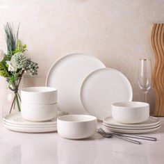 a white table setting with plates, cups and utensils on the countertop