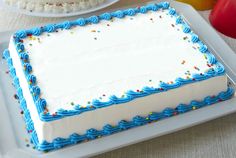 a blue and white cake sitting on top of a table next to a plate filled with fruit