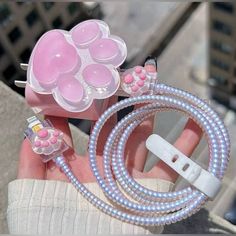 a hand holding a pink and white cell phone charger