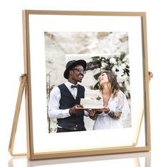 a man and woman holding a cake in front of a white background with a wooden frame