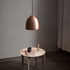 a table with a cup on it and a lamp hanging over the table next to it