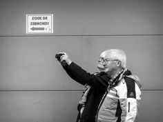 an older man taking a selfie with his camera in front of a sign that says zoo de zerhoni