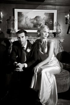 a man and woman sitting next to each other in front of a painting on the wall