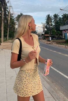 a woman is walking down the street with an umbrella in her hand while talking to someone