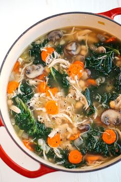 a pot full of soup with carrots, spinach and mushrooms