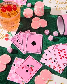 pink playing cards and dices on a green tablecloth with other items around them