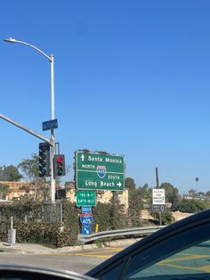 traffic lights and street signs at an intersection in santa monica, california on a sunny day