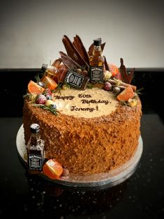 a birthday cake is decorated with candies and liquor bottles on the top, sitting on a table