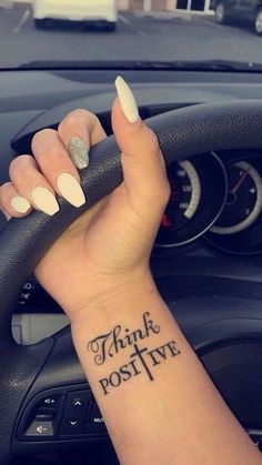 a woman's wrist with the words think positive tattooed on her left arm and an arrow