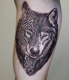 a black and white tattoo with a wolf's head on the leg, in celtic style