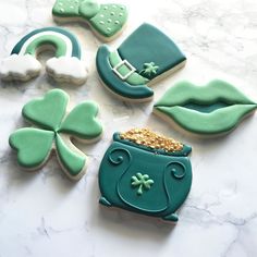 decorated cookies with green and white frosting on a marble countertop next to shamrocks