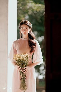 a woman in a pink dress holding a bouquet of flowers